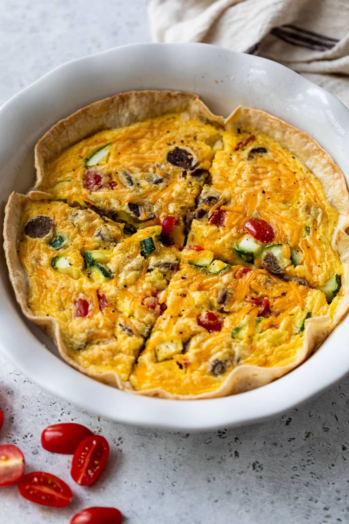 side view of a sliced tortilla quiche in a white pie plate.