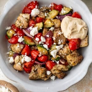 overhead view of air fryer greek chicken and vegetables in a large white bowl.