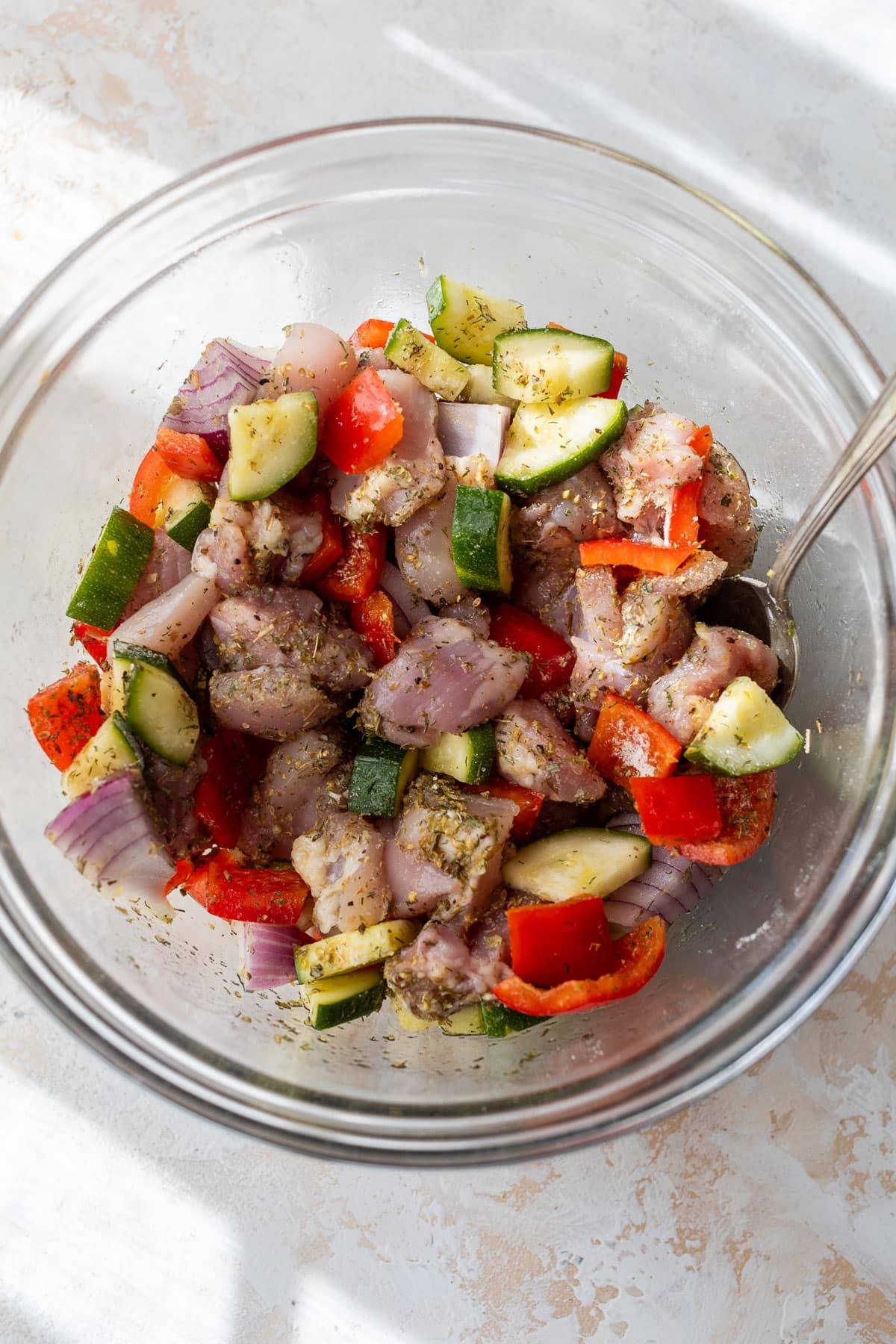 overhead view of the ingredients for air fryer Greek chicken in a large glass bowl.