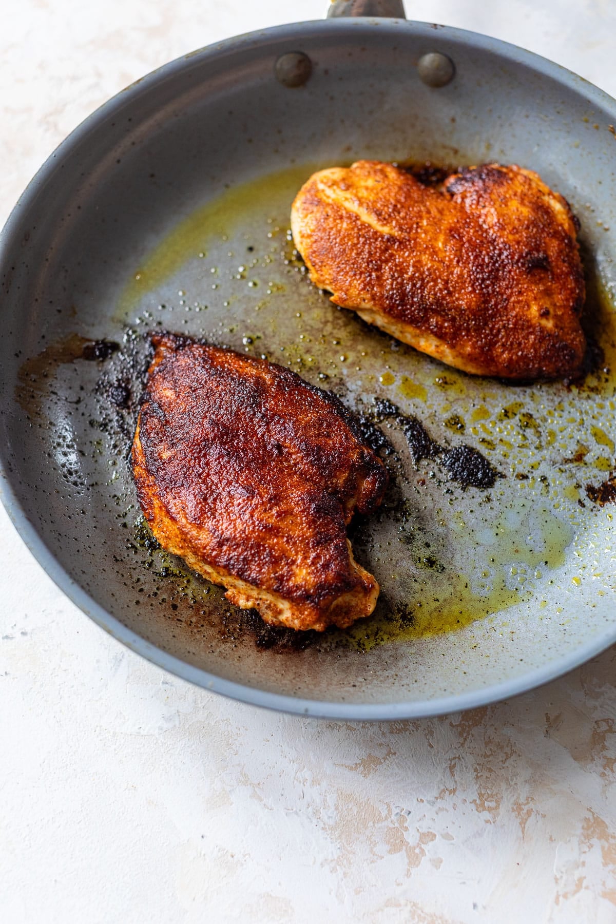 overhead view of taco-seasoned chicken breasts searing in a pan.
