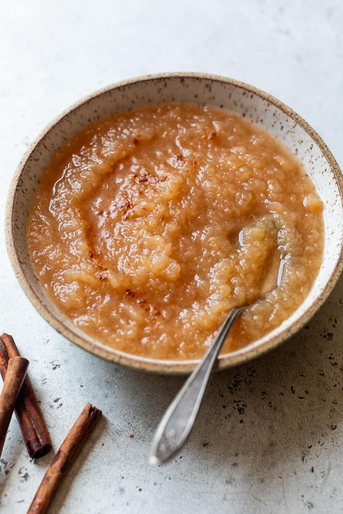 side view of a spoon in a bowl of homemade applesauce.