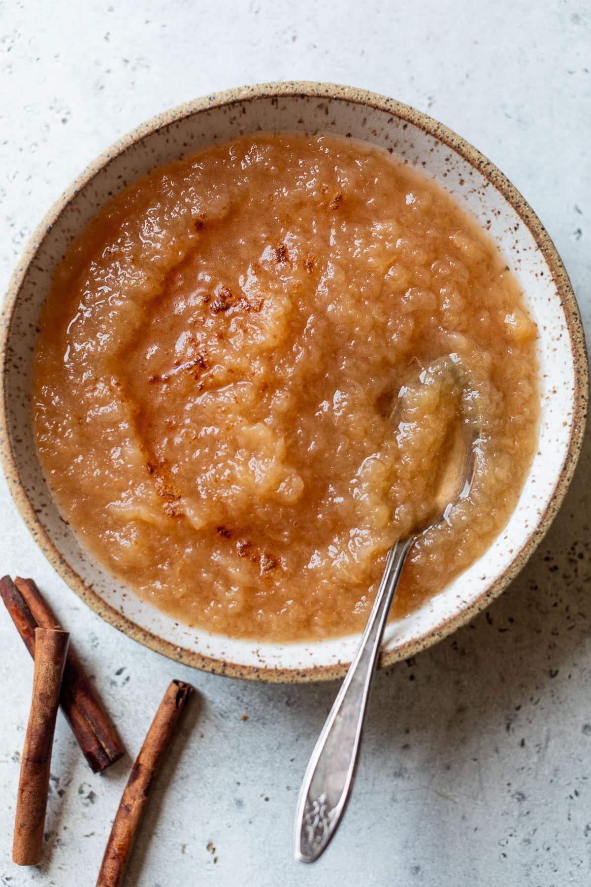 overhead view of a spoon in a bowl of homemade applesauce.