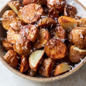 side view of a bowl full of parmesan roasted potatoes.