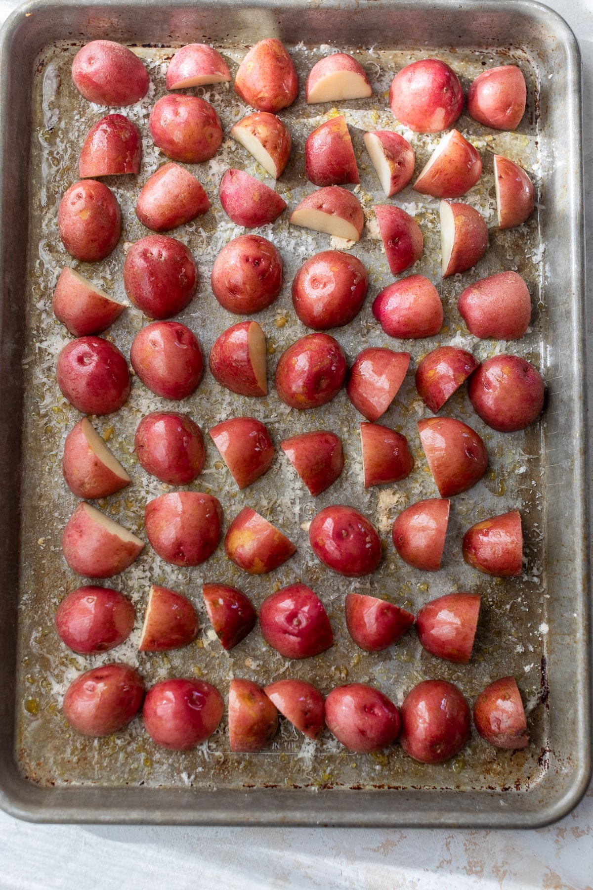 overhead view of halved potatoes cut side down on a baking sheet.