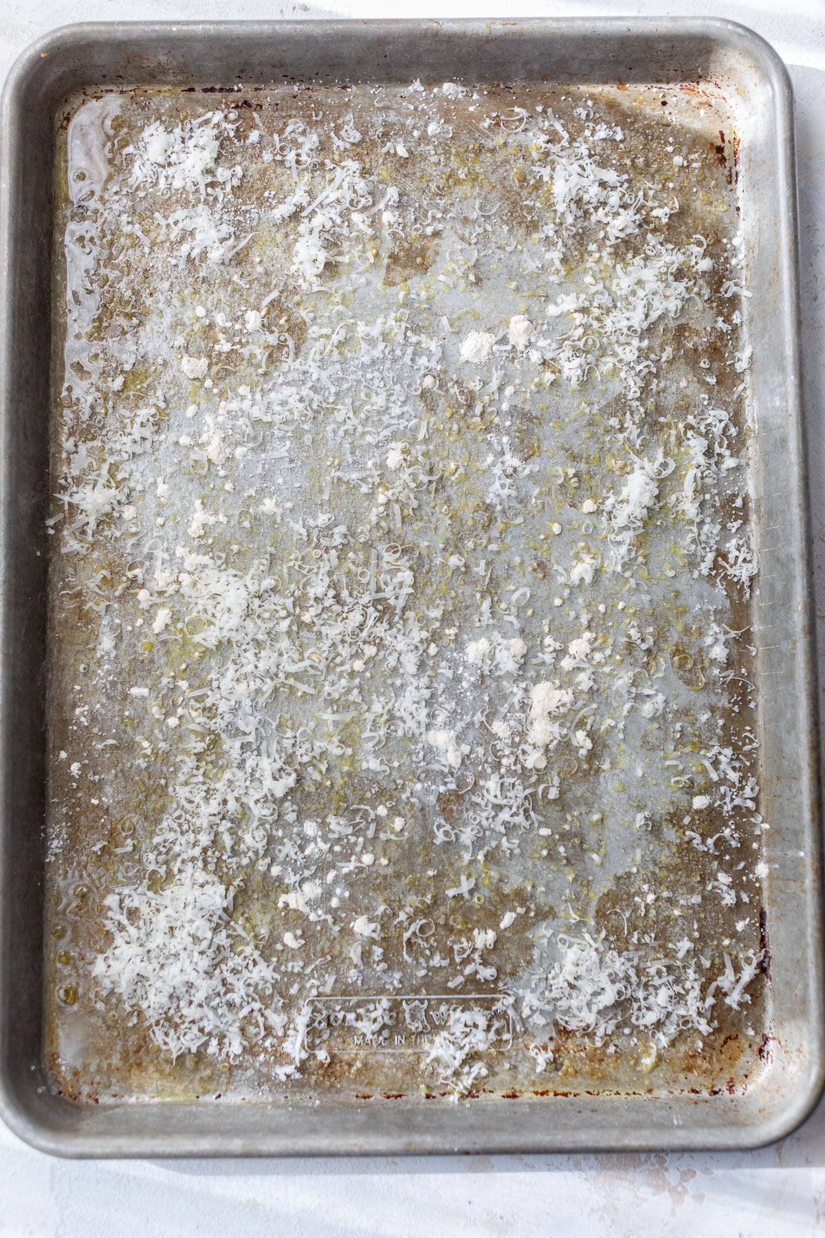 overhead view of grated parmesan cheese sprinkled over a baking sheet.