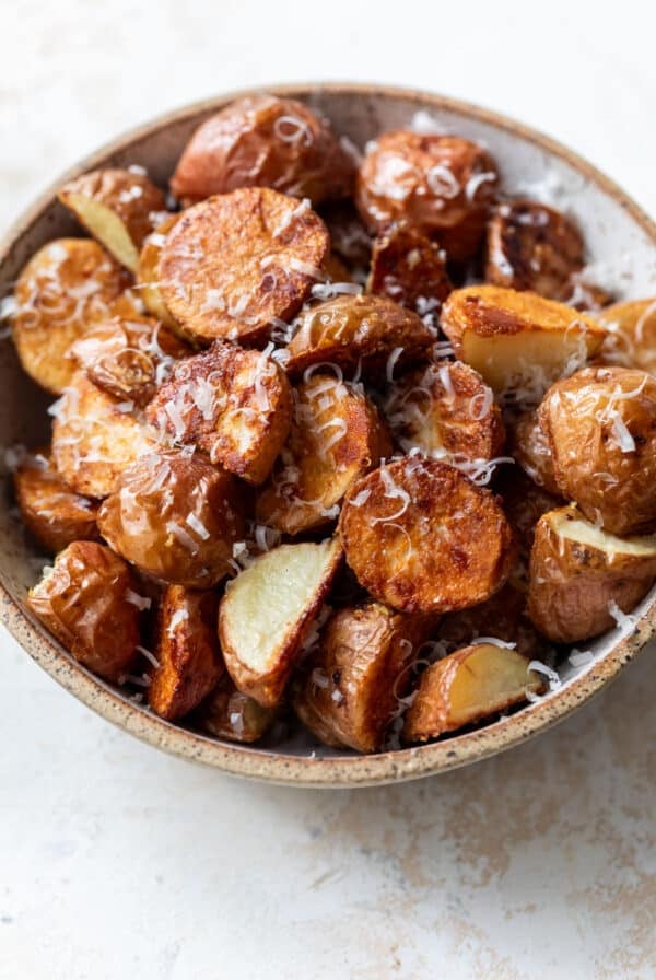 side view of a bowl full of parmesan roasted potatoes.