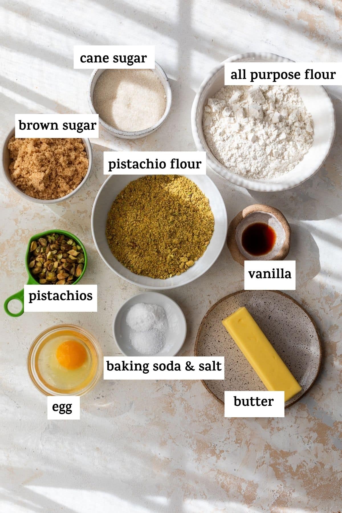 overhead view of the ingredients for pistachio cookies in bowls with labels.