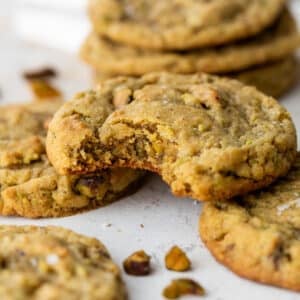 close up on a pistachio cookie with a bite taken out of it.