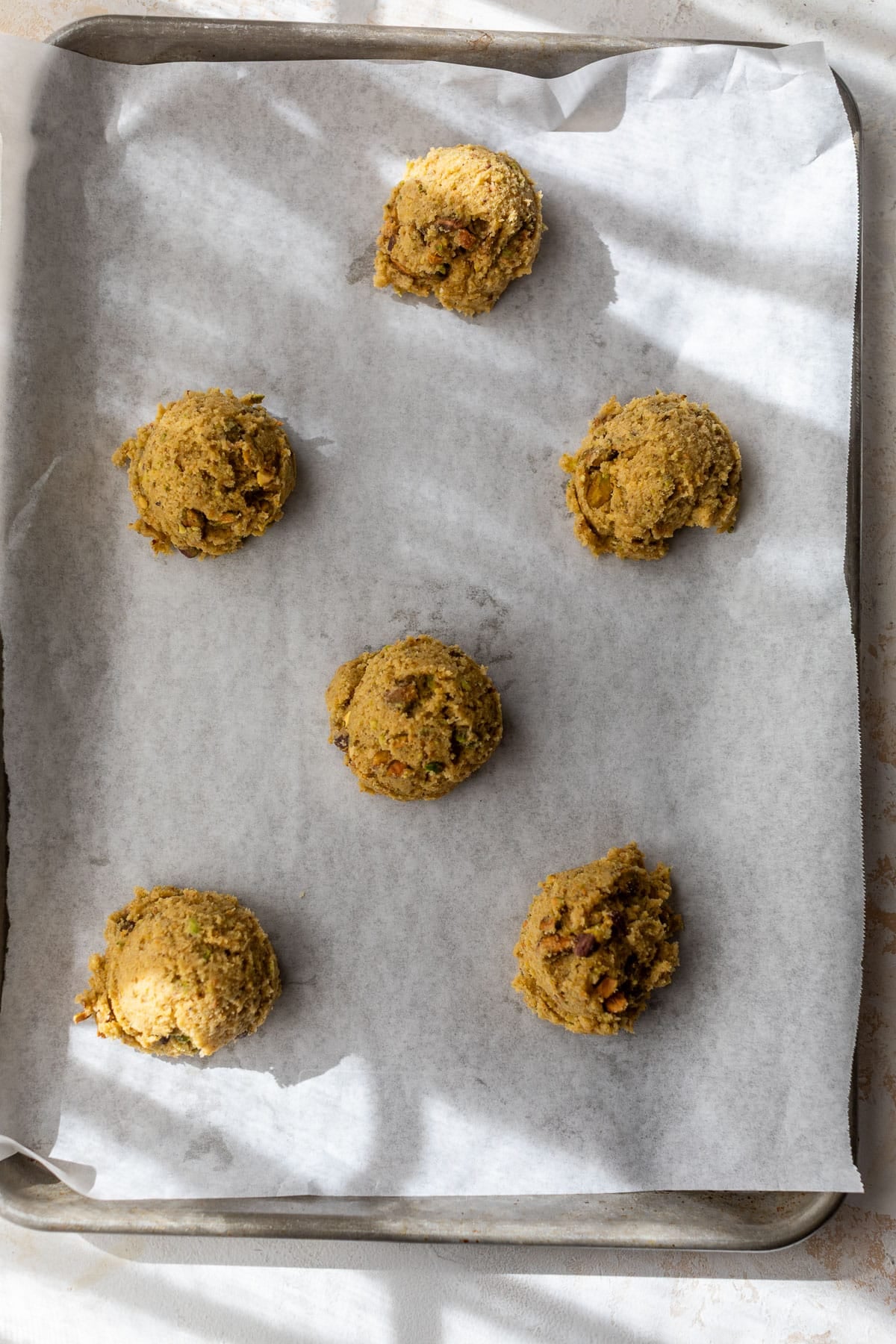 overhead view of pistachio cookie dough balls on a baking sheet.