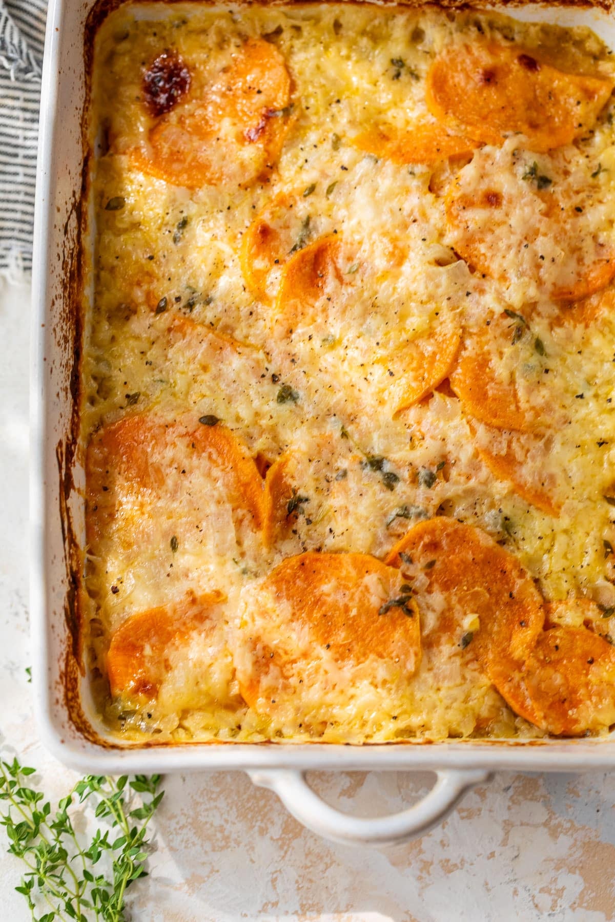 overhead view of baked scalloped sweet potatoes in a casserole dish.