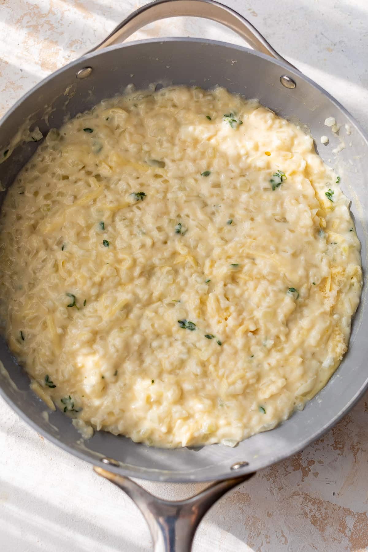 overhead view of a creamy cheese sauce for scalloped sweet potatoes in a skillet.