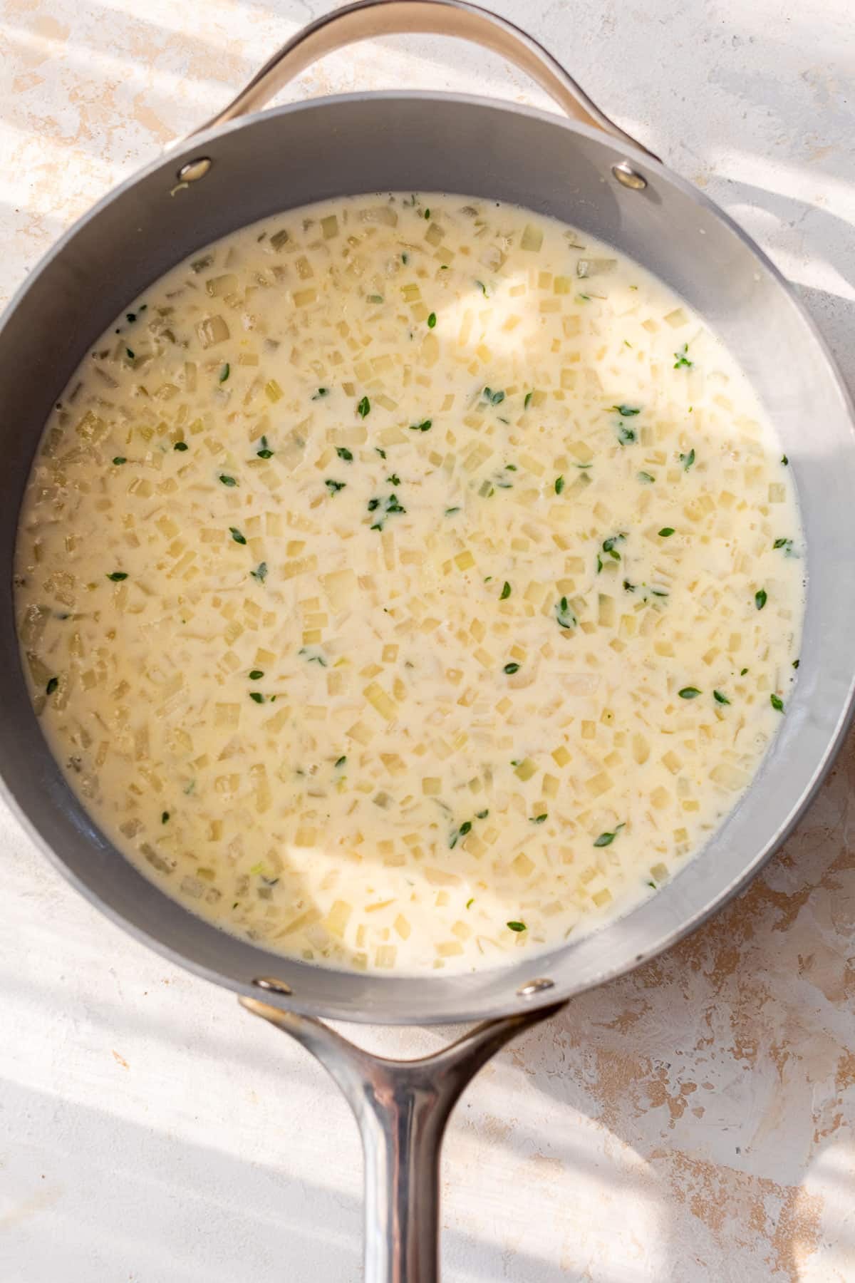 overhead view of a cream sauce for scalloped sweet potatoes in a skillet.