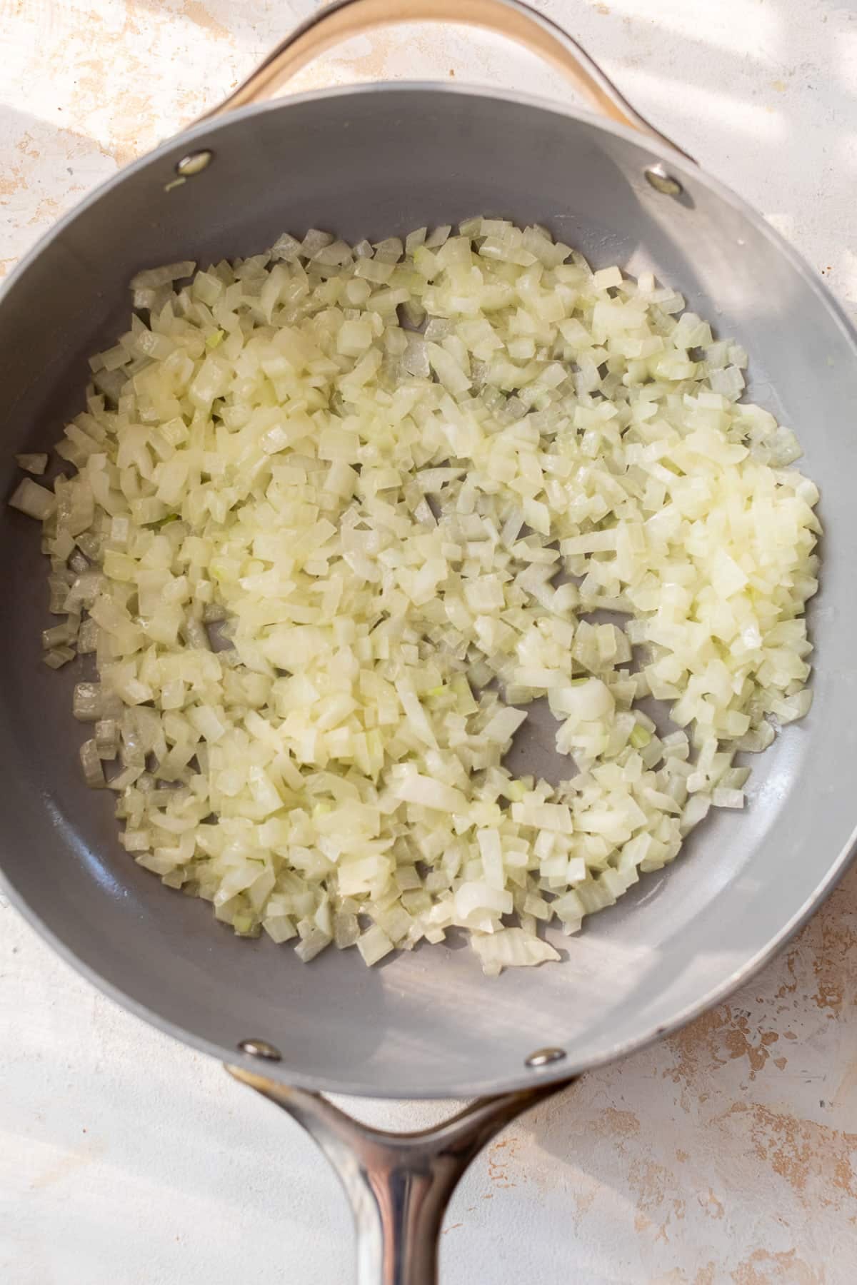 overhead view of a chopped onions cooking in a skillet.