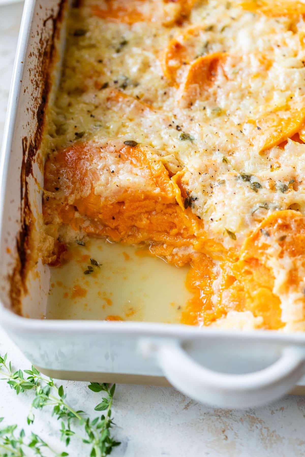 side view of baked scalloped sweet potatoes in a casserole dish.